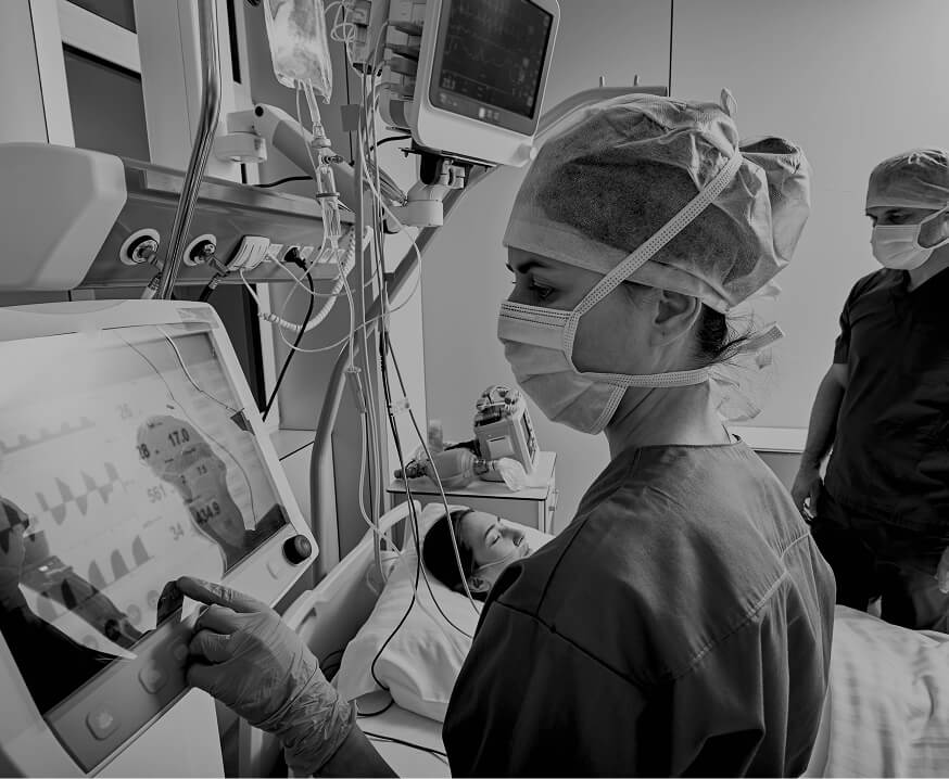 Surgical team operating medical monitoring equipment during a procedure, representing precision machined components for medical devices and equipment