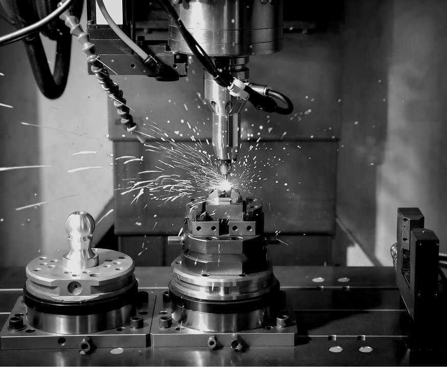 CNC milling operation with spark discharge cutting a workpiece mounted on a precision fixture plate, representing OEM machining and custom workholding solutions